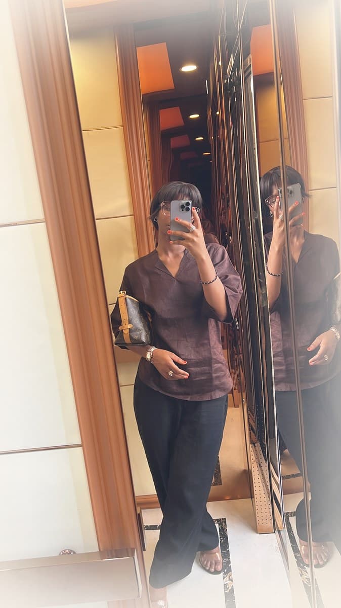 LJ look — brown V-neck blouse with wide-leg black trousers, styled with a monogram bag